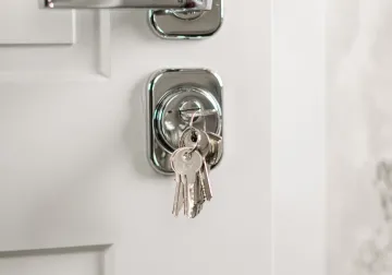 Manilla metálica y llaves en una puerta blanca